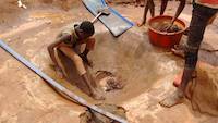 Child trying to recover all particles of gold from concentrates