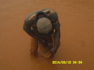 Miner panning for gold with traditional wooden bowl in Ghana